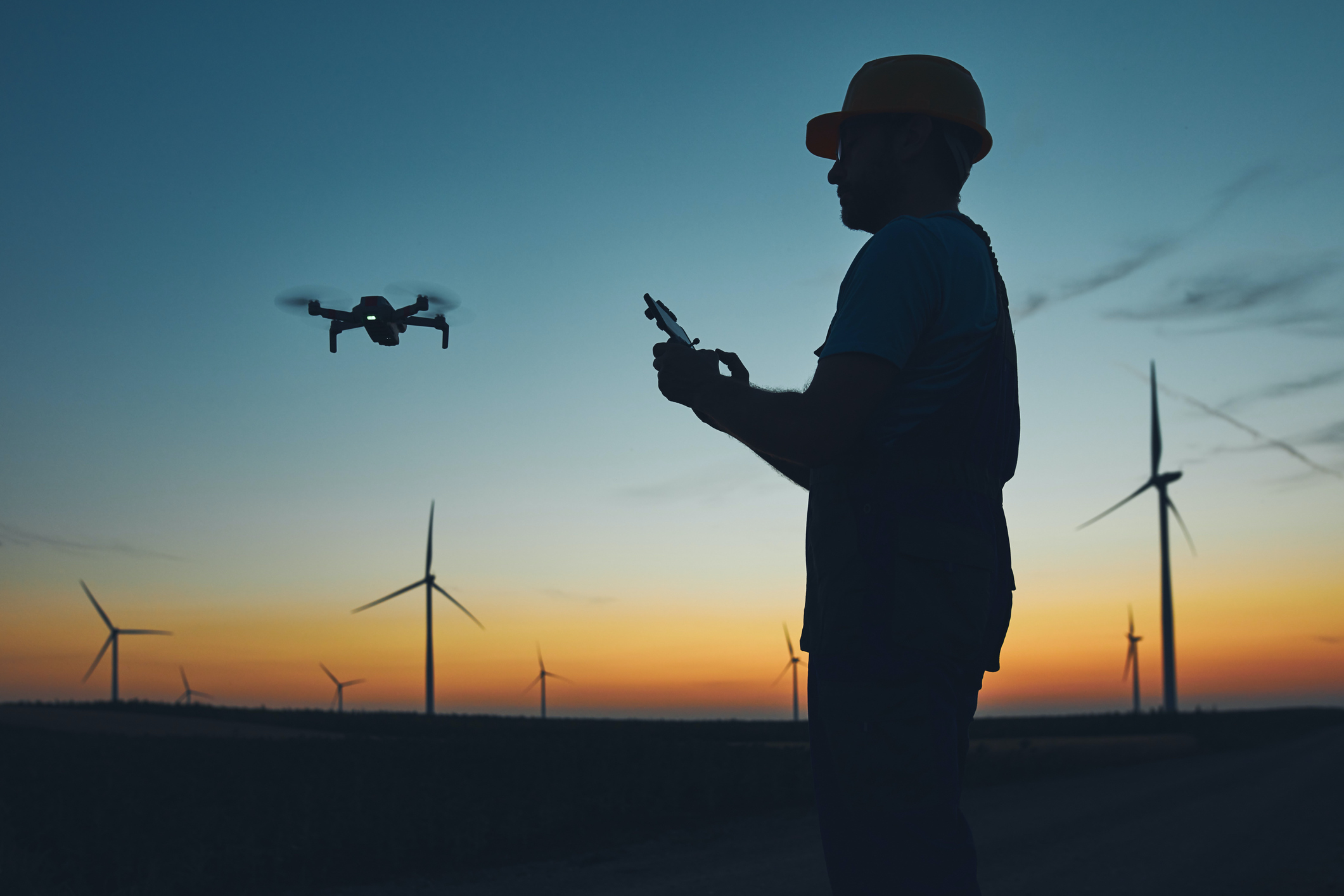 An engineer operates a drone at a wind farm site.
